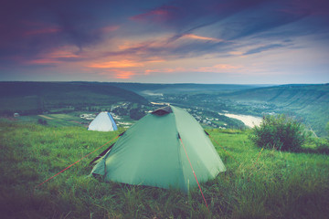 Tourist tent on green meadow at sunset. Camping background.