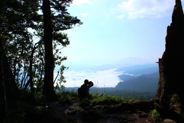 Obraz premium The young traveler photographs the landscape at the edge of the cliff