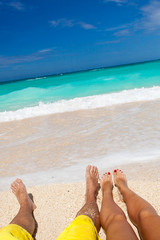 Fototapeta na wymiar Male and female legs on tropical beach