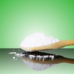 natural sugar in wooden spoon in green background