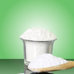 natural sugar in container and wooden spoon in green background