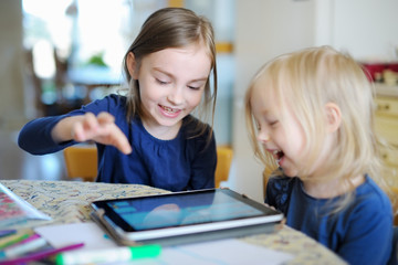 Two little sisters playing with a digital tablet