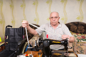 Fototapeta na wymiar Senior Man with Measuring Tape at Sewing Machine