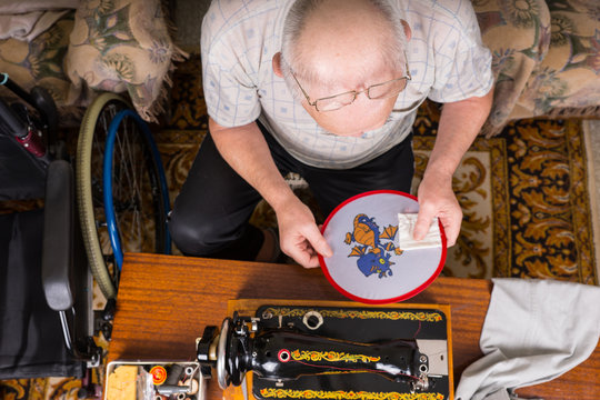 Senior Man Inspecting Needlepoint Work