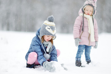 Fototapeta na wymiar Two funny adorable little sisters in winter park