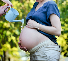 babybauch wird erfrsicht durch gießkanne © ilfotokunst