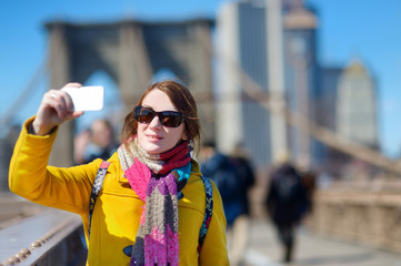 Young woman taking a selfie on Brooklyn Bridge