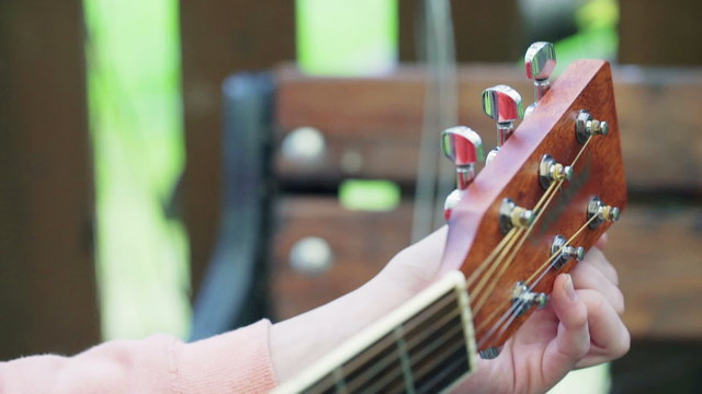 Girl touching tuning keys and tune the guitar
