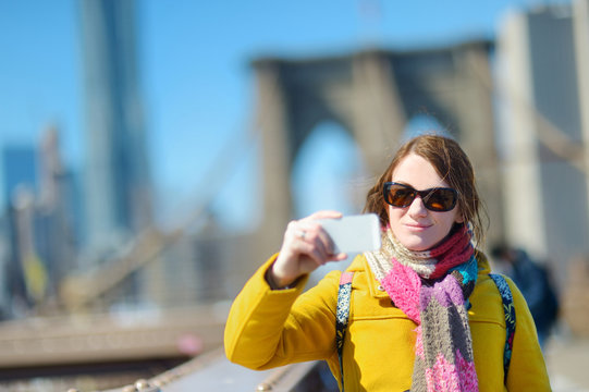 Young woman taking a selfie on Brooklyn Bridge
