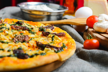 Delicious homemade pizza with cheese meat and mushrooms on a