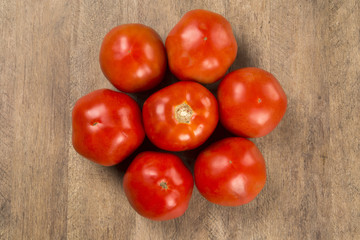 Some tomatoes over a wooden surface on a tomato field as backgro