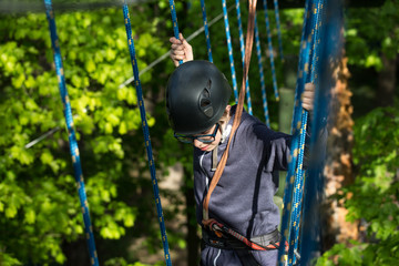 teenager climbing a rope park, boy climbing in adventure park 