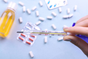 Hand holding thermometer on pills background