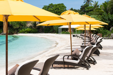 Sun umbrellas and beach chairs on tropical beach