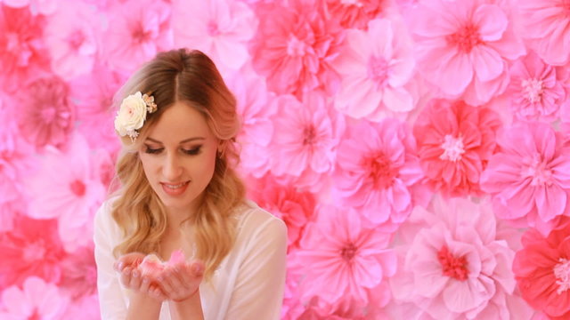 Beautiful woman blowing rose petals on flower background