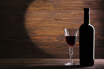 Wineglass and bottle on wooden background