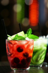 Glasses of cocktails in bar on bright blurred background