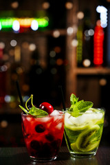 Glasses of cocktails in bar on bright blurred background