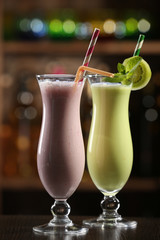 Glasses of fruit cocktails in bar on bright blurred background