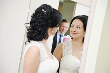 bride and groom standing in front of a mirror