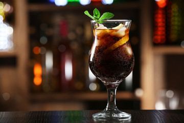 Glass of cocktail in bar on bright blurred background
