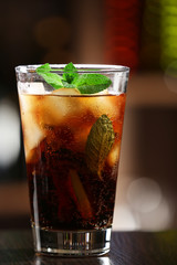 Glass of cocktail in bar on bright blurred background