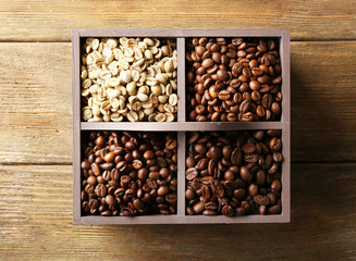 Coffee beans in box on wooden table, top view