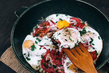 Cooking Fried eggs with tomatoes and onions in a pan