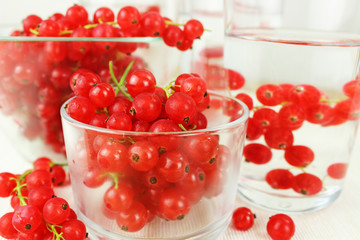 Johannisbeeren in Schale aus Glas auf Esstisch in Wasserglas und in Karaffe mit Wasser