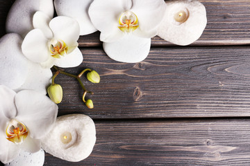 Spa stones and orchid flower on wooden background