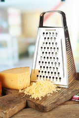 Grated cheese on wooden cutting board on blurred background