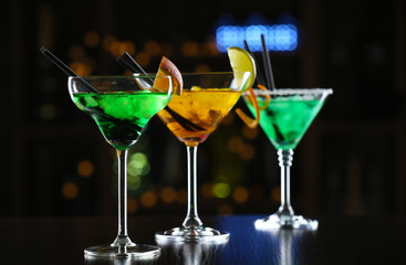 Glasses of cocktails on bar background