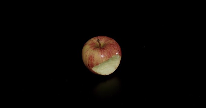 Red apple with a bite taken on black background