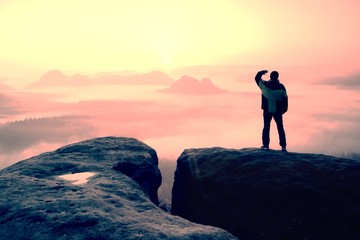 Obraz premium Moment of loneliness. Man on the rock empires and watch over the misty and foggy morning valley to Sun
