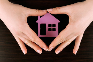 Female hands with model of house on wooden table background
