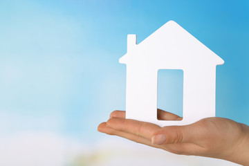 Female hand with model of house on color background