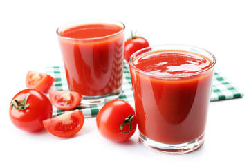 Glasses of fresh tomato juice on checkered napkin, isolated on white