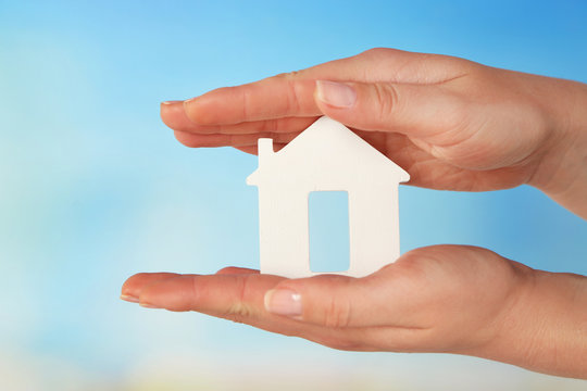 Female hands with model of house on color background