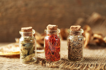 Assortment of spices in glass bottles on wooden background