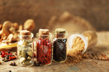 Assortment of spices in glass bottles on wooden background