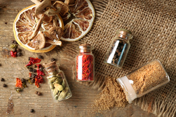 Fototapeta na wymiar Assortment of spices in glass bottles on wooden background