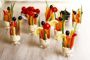 Snack of vegetables in glassware on wooden background