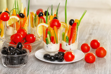 Snack of vegetables in glassware on wooden background