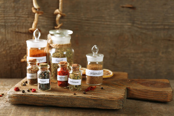 Obraz na płótnie Canvas Assortment of spices in glass bottles on cutting board, on wooden background