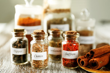 Assortment of spices in glass bottles on wooden background