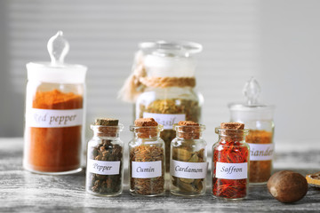 Assortment of spices in glass bottles on wooden table, on light background