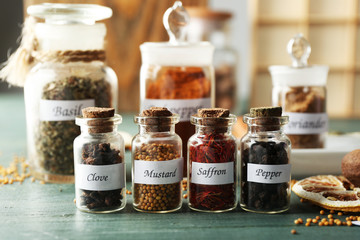 Assortment of spices in glass bottles on wooden background