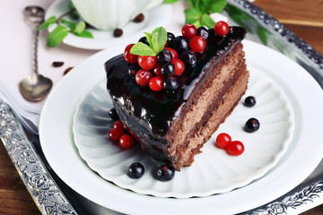 Delicious chocolate cake with berries on plate on table close up