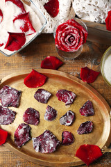 Making candied rose flower petals with egg whites and sugar, on wooden background