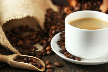 Cup of coffee with beans on table close up